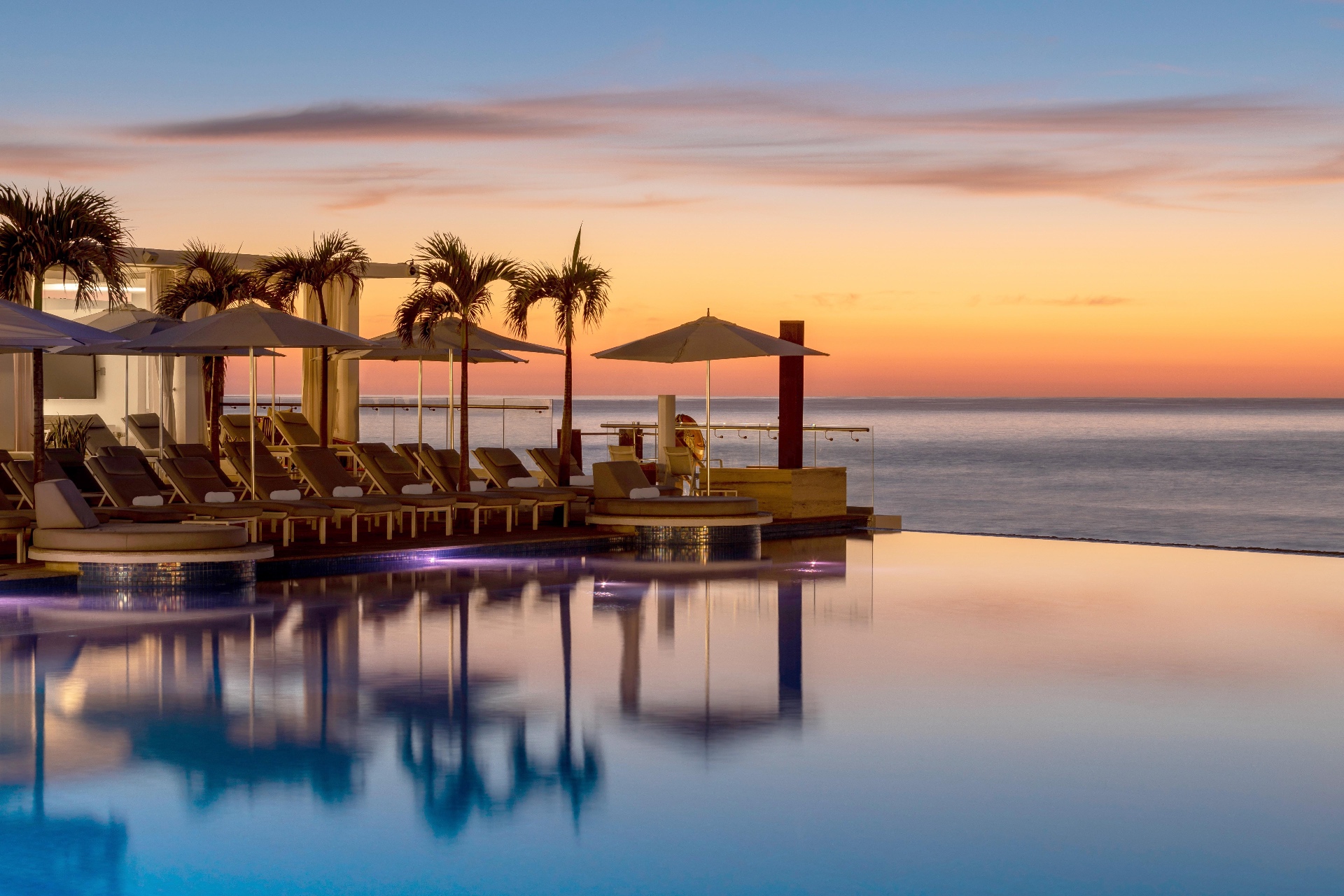 Luxury beachfront resort with infinity pool at sunset